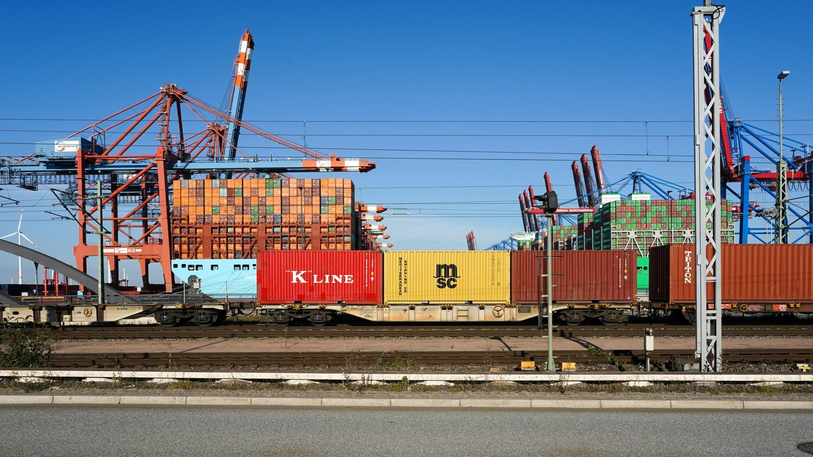 Colorful shipping containers and cranes at Hamburg port symbolize global trade and logistics.